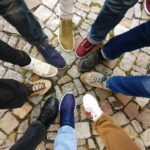 Circle of sneakers on cobblestone pavement representing diversity and urban fashion.