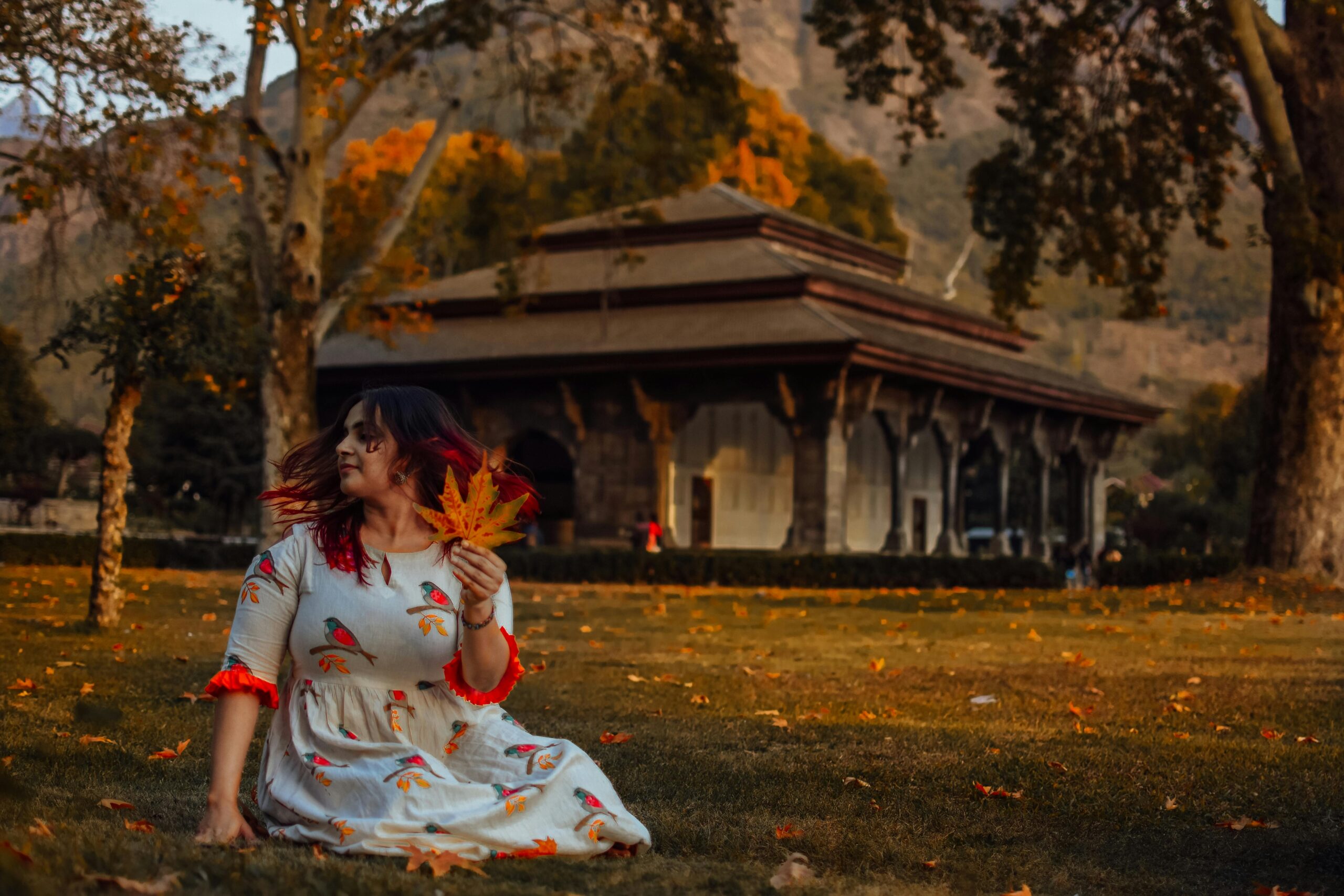 A woman elegantly poses in the autumn scenery of Nishat Bagh, Srinagar.